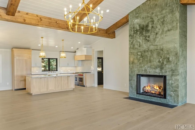 kitchen featuring pendant lighting, lofted ceiling with beams, range with two ovens, a center island, and light wood-type flooring