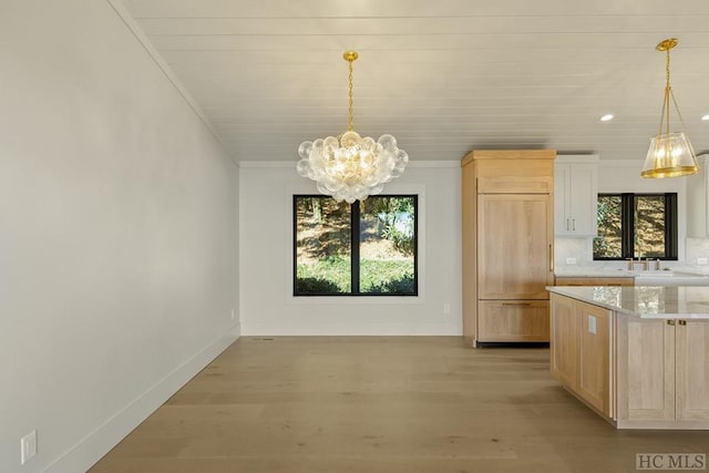 unfurnished dining area featuring light wood-type flooring, a chandelier, and ornamental molding