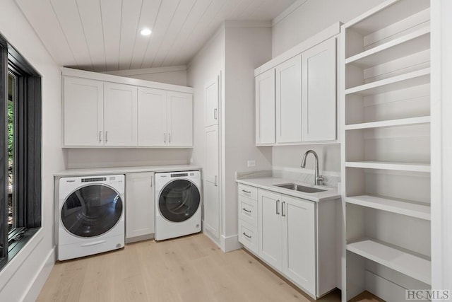 washroom featuring light hardwood / wood-style flooring, sink, washer and clothes dryer, and cabinets