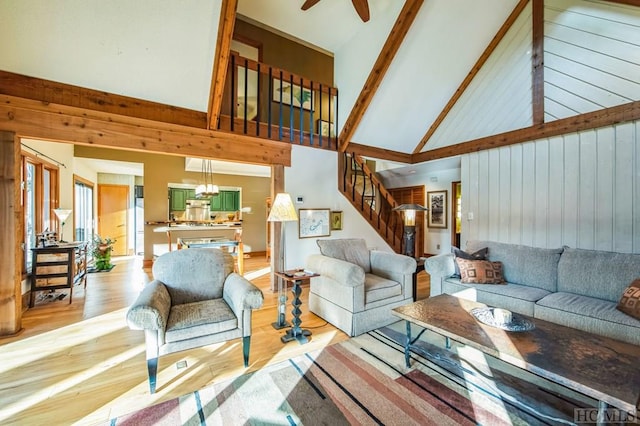 living room with light hardwood / wood-style floors, beam ceiling, high vaulted ceiling, and ceiling fan