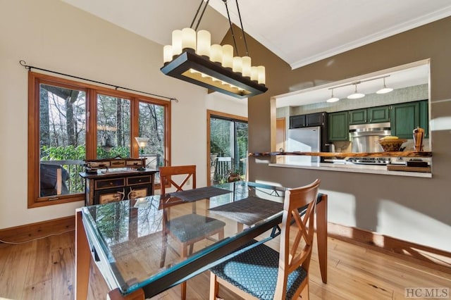 dining room featuring light hardwood / wood-style flooring, crown molding, an inviting chandelier, and lofted ceiling