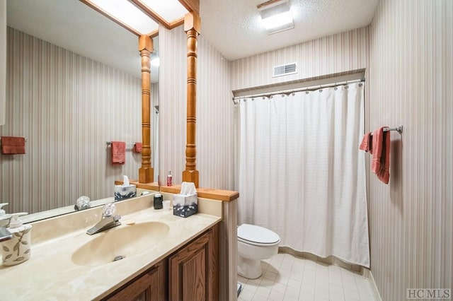 bathroom with a shower with curtain, toilet, a textured ceiling, and vanity