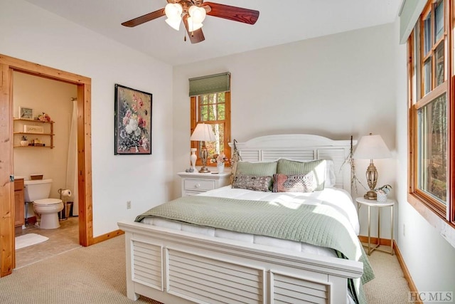 bedroom featuring ensuite bathroom, light carpet, and ceiling fan