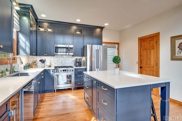 kitchen featuring a kitchen island, tasteful backsplash, blue cabinets, sink, and stainless steel appliances