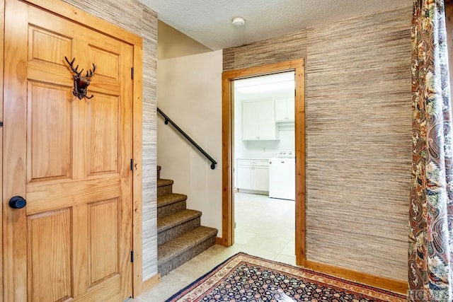 stairway featuring washer / clothes dryer, tile patterned floors, and a textured ceiling