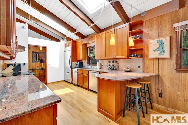 43 Chimney Pt, Lake Toxaway, NC 28747 - kitchen featuring stainless steel appliances, light stone counters, a kitchen bar, a skylight, and wooden walls