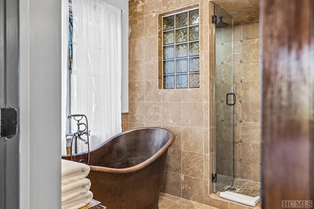 bathroom with a shower with door and tile walls