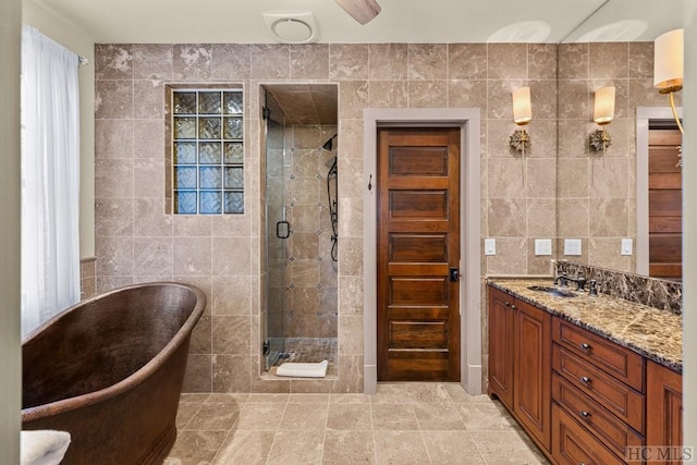 bathroom with tile walls, vanity, and plus walk in shower