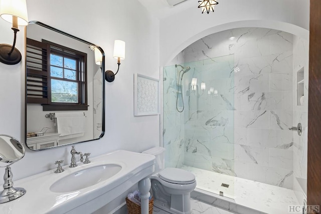 bathroom featuring tiled shower, toilet, and sink