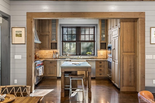 kitchen with stainless steel appliances, light stone countertops, decorative backsplash, and wood walls