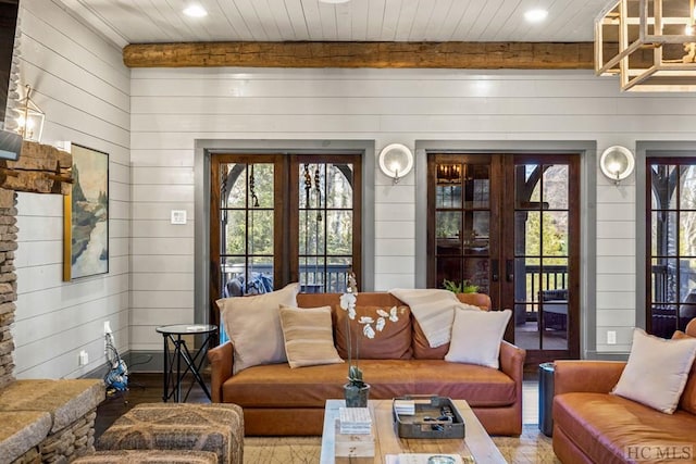 living room featuring french doors, beamed ceiling, and wood walls