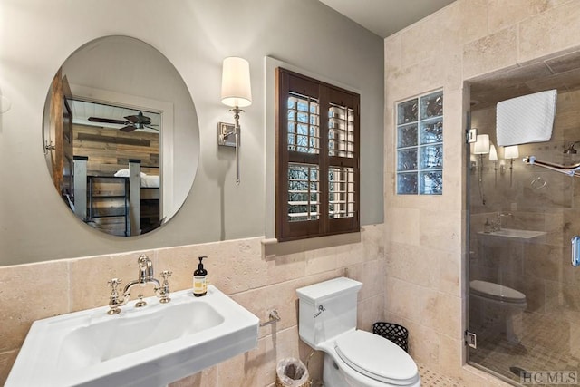 bathroom with ceiling fan, toilet, sink, and tile walls