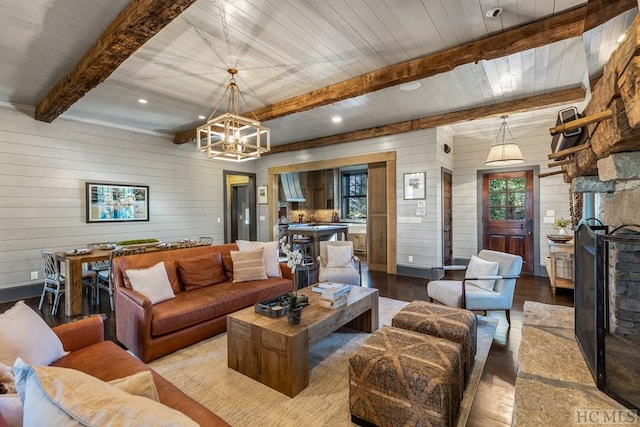 living room featuring beamed ceiling, wooden walls, a chandelier, and light hardwood / wood-style floors