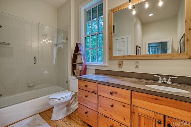 full bath featuring vanity, toilet, and combined bath / shower with glass door