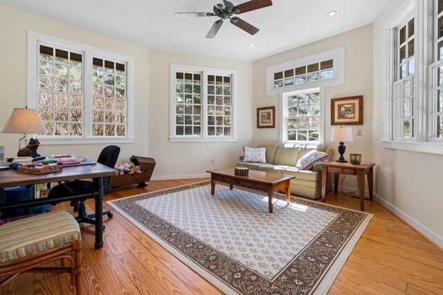 bedroom featuring a raised ceiling, wood finished floors, recessed lighting, a stone fireplace, and baseboards