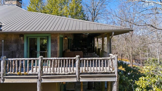 back of property featuring a porch, a yard, stone siding, and metal roof