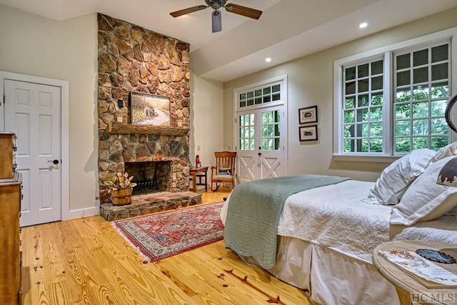 bedroom featuring wood finished floors, recessed lighting, french doors, a stone fireplace, and vaulted ceiling