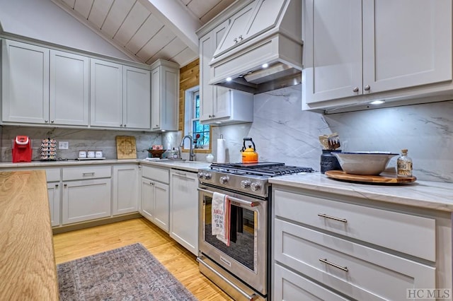 kitchen featuring premium range hood, light wood-style flooring, a sink, dishwasher, and gas range