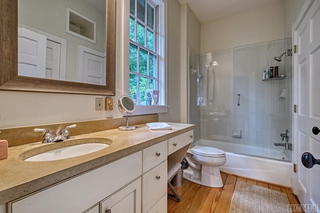 full bath with toilet,  shower combination, wood finished floors, and vanity