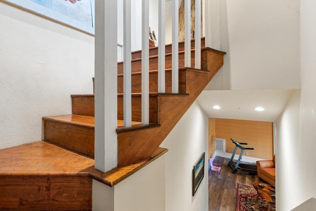 stairway featuring heating unit, recessed lighting, wood finished floors, and visible vents