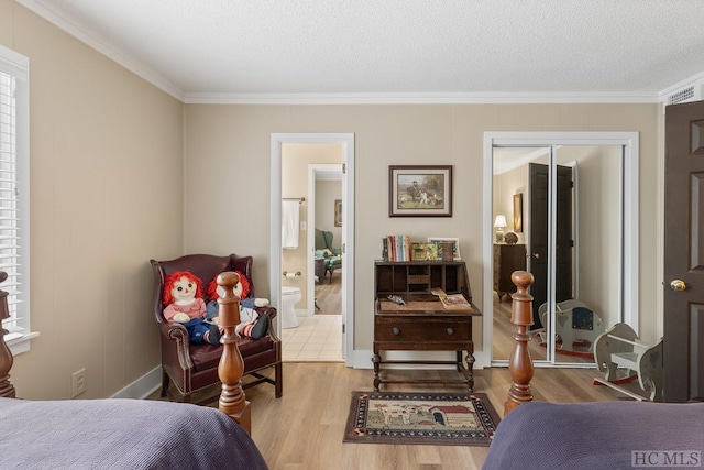 bedroom featuring ensuite bath, a closet, crown molding, and light hardwood / wood-style floors