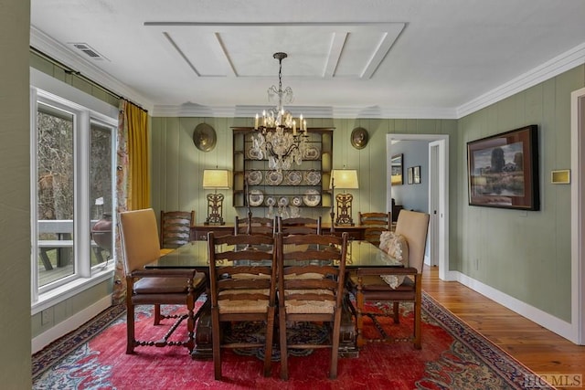 dining area featuring an inviting chandelier, hardwood / wood-style floors, crown molding, and plenty of natural light