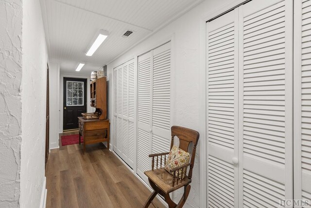 corridor with dark wood-type flooring and ornamental molding