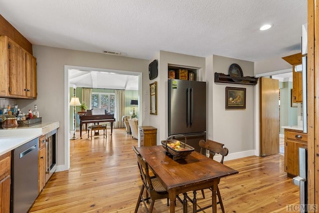 dining area with light hardwood / wood-style floors, a textured ceiling, and indoor bar