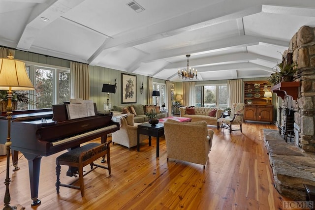 living room featuring light hardwood / wood-style floors, a stone fireplace, lofted ceiling with beams, and a notable chandelier