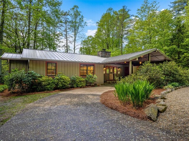 145 Island Point Rd, Lake Toxaway, NC 28747 - mid-century modern home with a chimney, board and batten siding, asphalt driveway, and metal roof