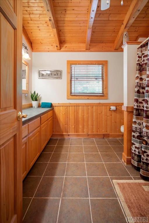 bathroom featuring toilet, vaulted ceiling with beams, wood ceiling, vanity, and wooden walls