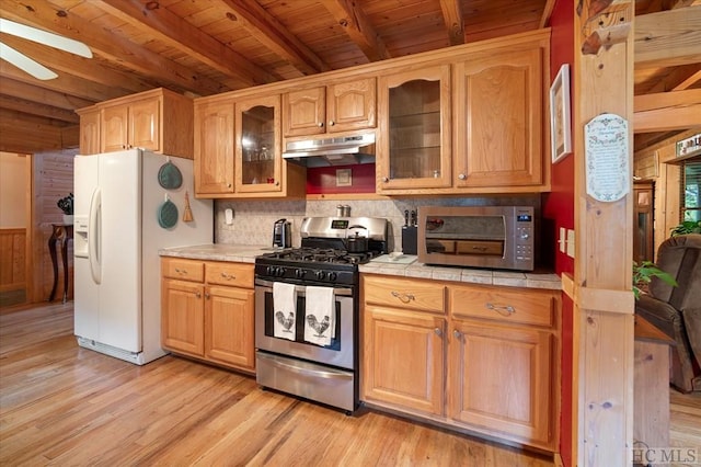 kitchen with wood ceiling, appliances with stainless steel finishes, tile counters, beamed ceiling, and light wood-type flooring