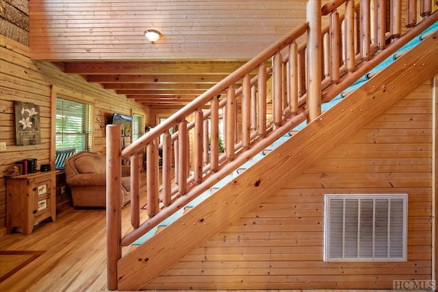 stairs featuring hardwood / wood-style floors and wooden walls