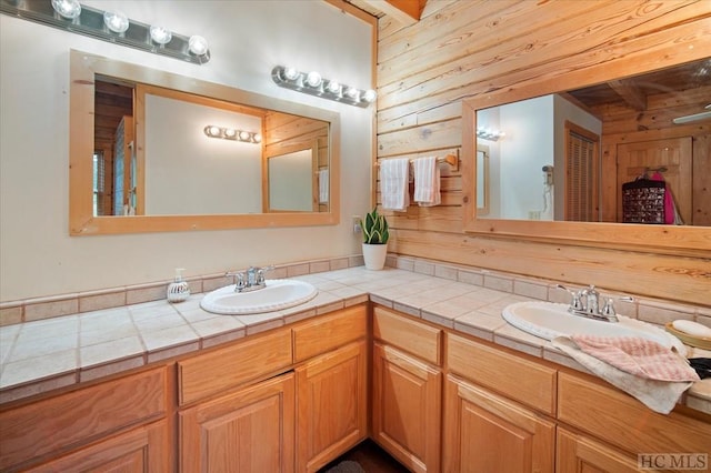 bathroom with beamed ceiling, vanity, and wood walls