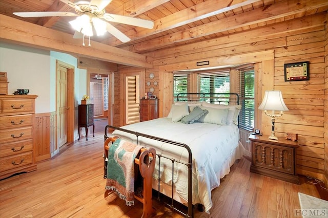 bedroom with wood walls, light wood-type flooring, wooden ceiling, ceiling fan, and beam ceiling