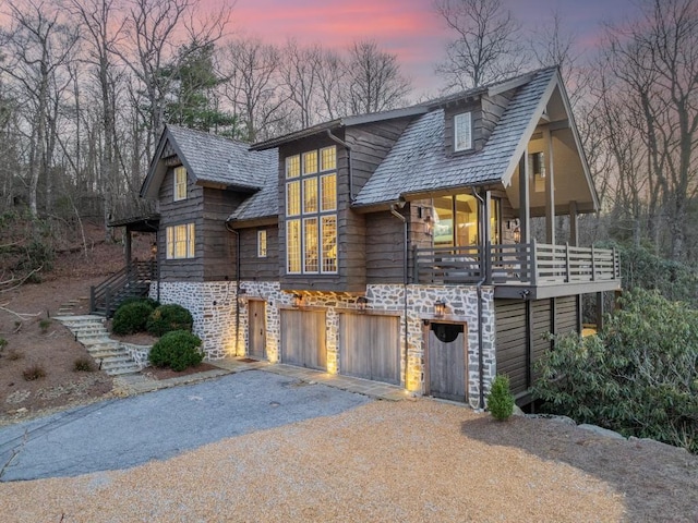 view of front of house with a garage, stone siding, stairs, and driveway