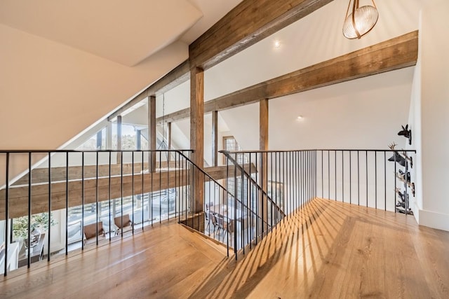 hallway featuring lofted ceiling with beams, a wall of windows, and wood finished floors