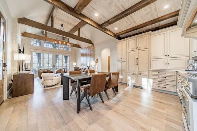 dining space with light wood-style floors, arched walkways, french doors, and beam ceiling