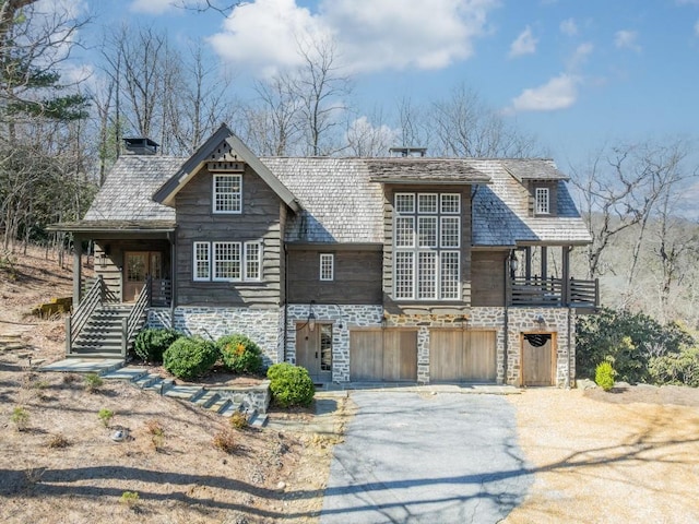 view of front of home featuring stone siding, aphalt driveway, and an attached garage