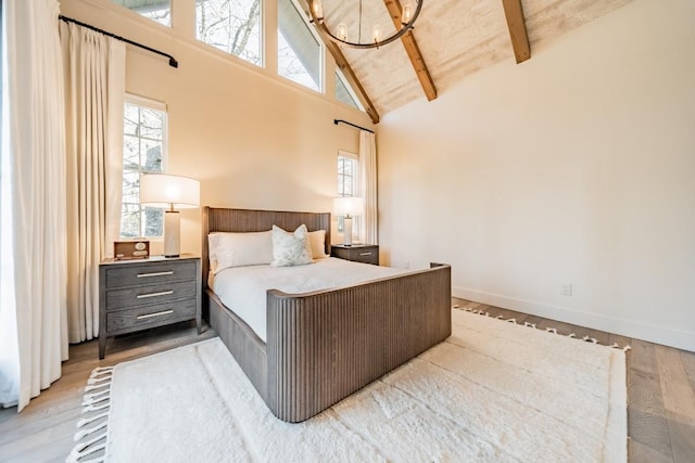 bedroom featuring an inviting chandelier, high vaulted ceiling, wood finished floors, and beamed ceiling