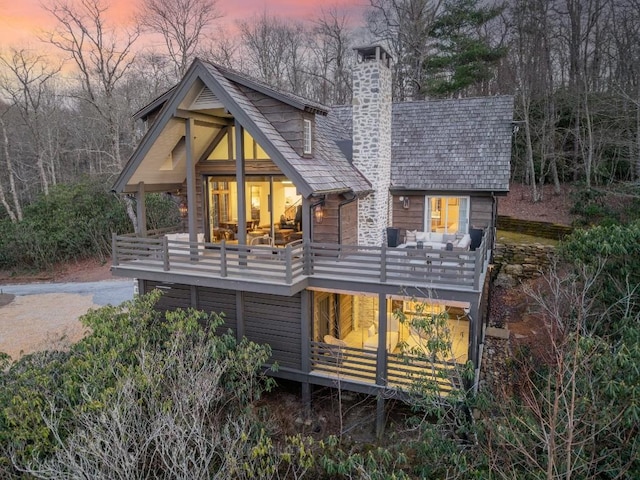 rear view of property featuring a chimney and a balcony