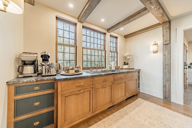 interior space featuring wood finished floors, beamed ceiling, a sink, and a wealth of natural light