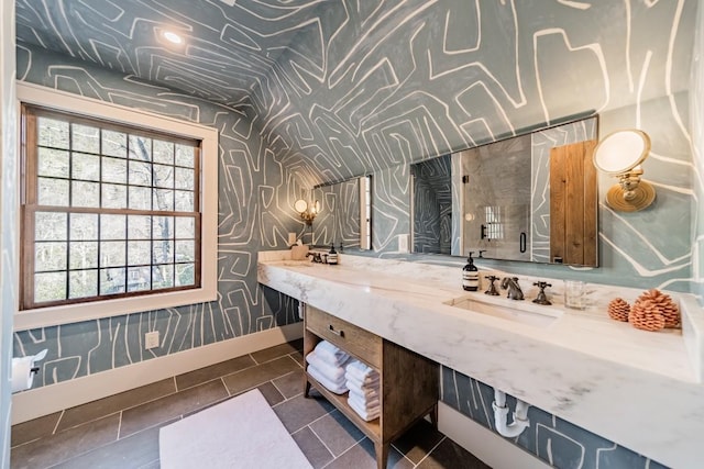 full bath with tile patterned flooring, a sink, baseboards, double vanity, and wallpapered walls