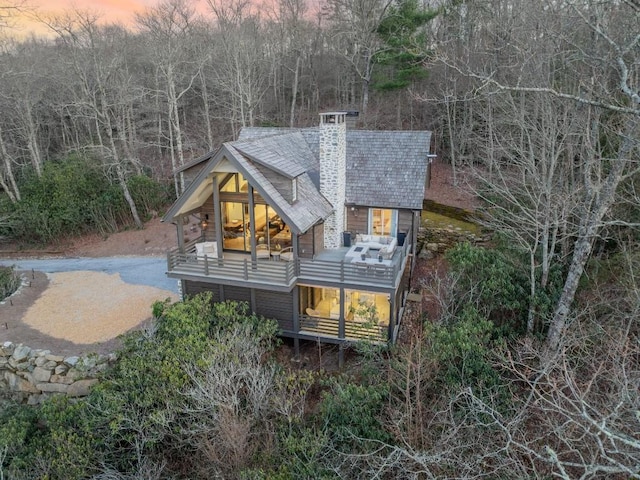 rear view of property featuring a chimney and a balcony