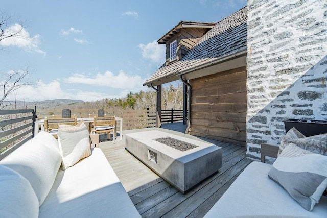 deck featuring an outdoor living space with a fire pit and fence