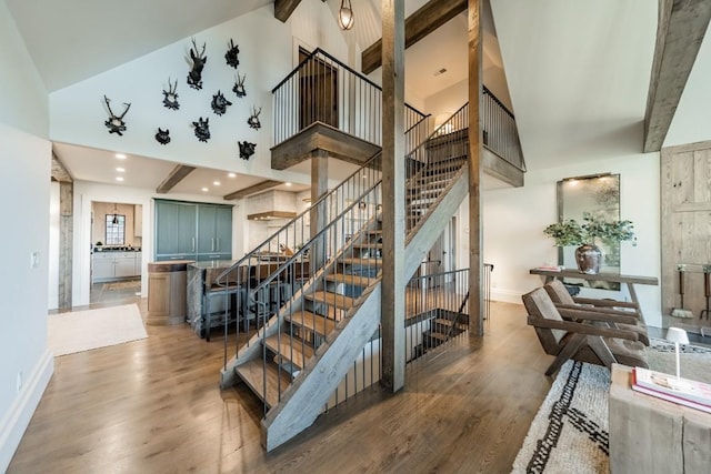 stairway featuring recessed lighting, baseboards, a high ceiling, and wood finished floors