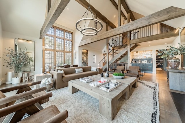 living area with a chandelier, wood finished floors, stairs, high vaulted ceiling, and beam ceiling