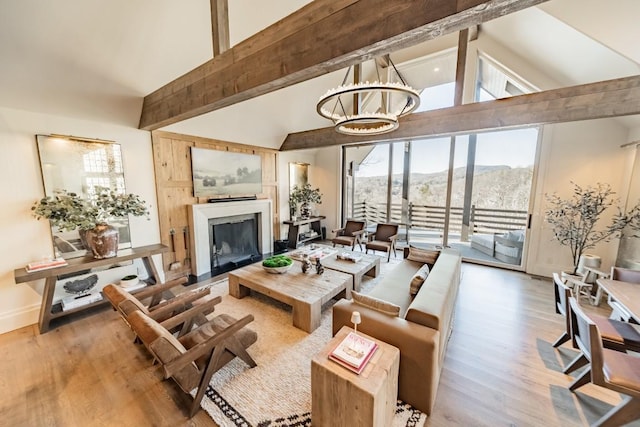 living room with vaulted ceiling with beams, a fireplace, wood finished floors, and a notable chandelier