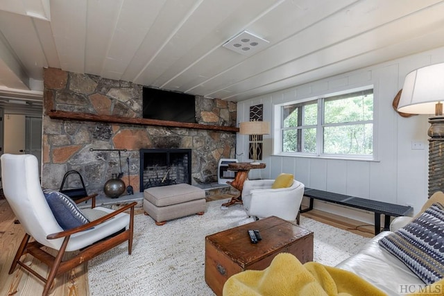 living room featuring a stone fireplace and wood finished floors