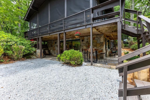 exterior space with outdoor dry bar, stone siding, a patio, and a deck